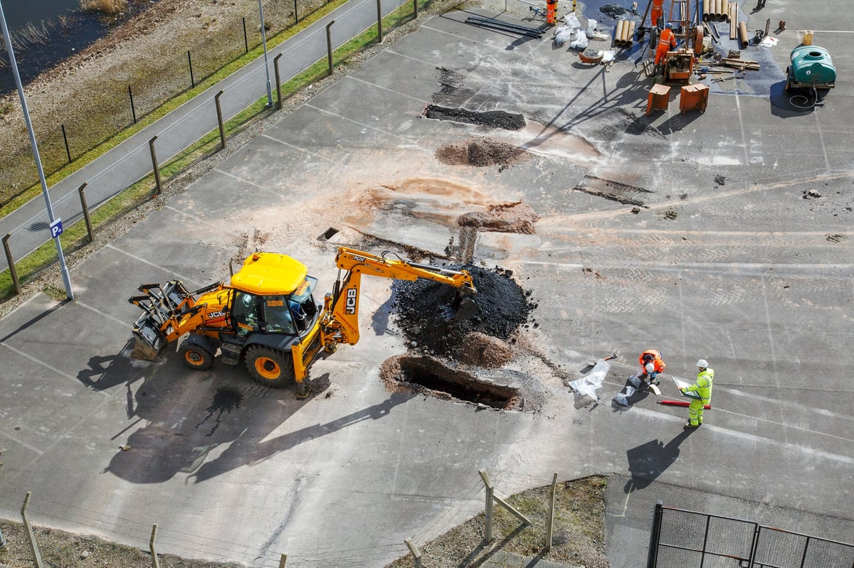 Cardiff, UK: March 10, 2016: Construction workers repairing the asphalt surface and drainage of a car park